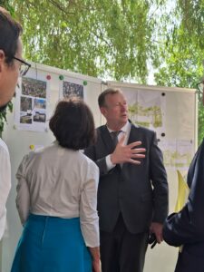 Alain Darbon, Maire de Saint-Léonard de Noblat, présente les plans d'aménagement du site de l'ancien hôpital devant des panneaux explicatifs, entouré de membres de la délégation.